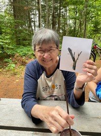Smiling person with art project in nature setting.