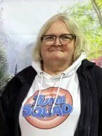 Person wearing Tune Squad hoodie, glasses, smiling outdoors
