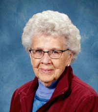 Elderly woman with glasses and white hair, smiling.