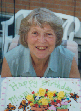 Elderly woman celebrating birthday with decorated cake.