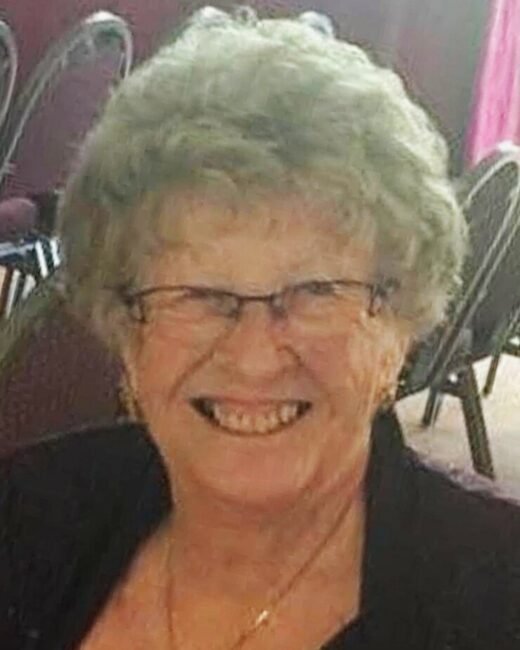 Smiling elderly woman with glasses and curly hair.