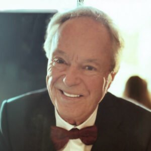 Smiling man with bow tie at event.