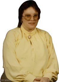 Person in yellow blouse with glasses, smiling.