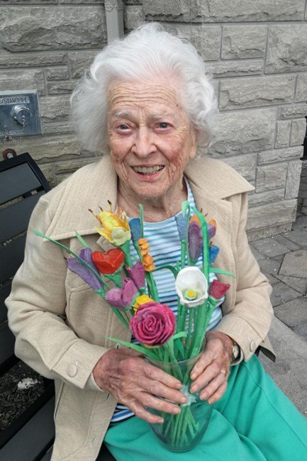 Elderly woman holding colorful bouquet outdoors.