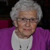 Smiling elderly woman with glasses and white hair.