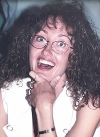 Smiling person with glasses and curly hair