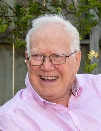 Smiling elderly man with glasses outdoors.
