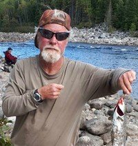 Man holding a fish by the river.