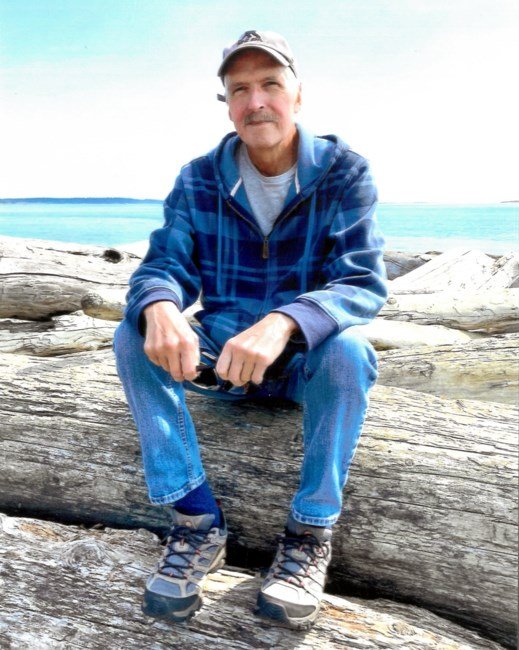 Man sitting on driftwood by the sea
