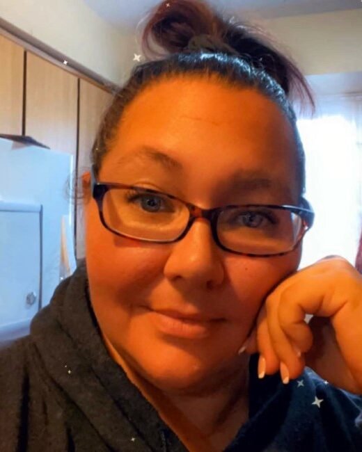 Person with glasses smiling in kitchen.