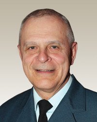 Smiling man in formal attire with neutral background.