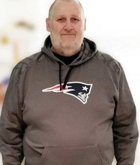 Man wearing Patriots hoodie, smiling at camera.