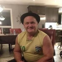 Smiling man in hat sitting indoors.