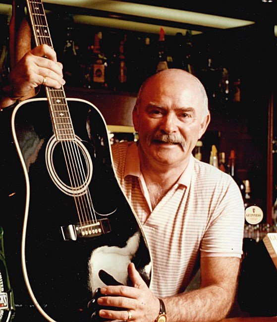 Man holding a black acoustic guitar in bar