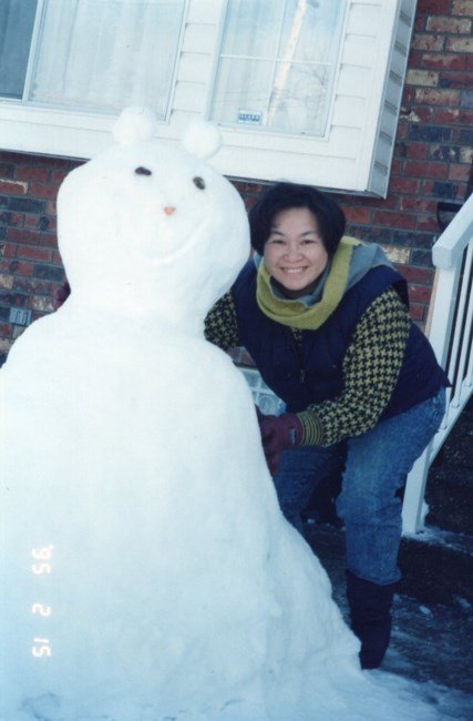Person smiling next to a snowman in winter.