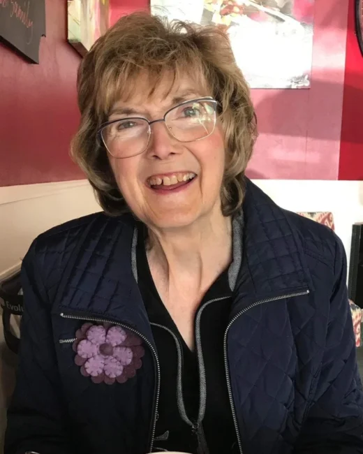 Smiling person wearing glasses sitting indoors.