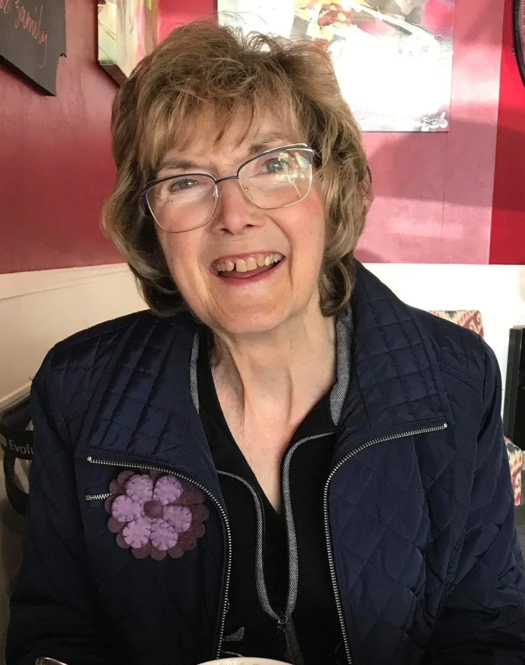Smiling person wearing glasses sitting indoors.