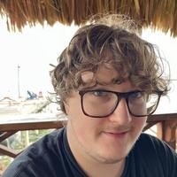 Person sitting under a thatched roof, wearing glasses.