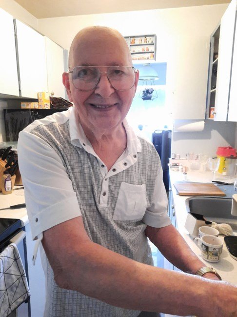 Smiling elderly man in a kitchen, preparing food.