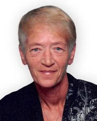 Elderly person in dark clothing smiling at camera.