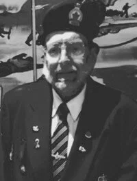 Elderly man in military attire, wearing a hat.
