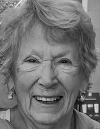 Elderly woman smiling warmly in black and white photo.