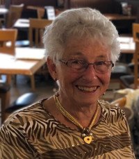 Smiling elderly woman in restaurant setting.
