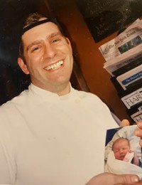Smiling man holding a baby photo