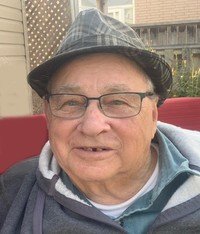 Smiling elderly man wearing glasses and a hat.