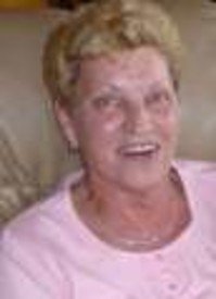 Smiling woman sitting on a couch, wearing pink shirt.