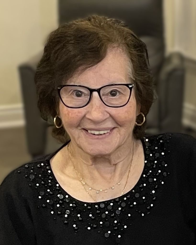 NERI, Nina Neri Elderly woman smiling, wearing glasses and dark blouse.