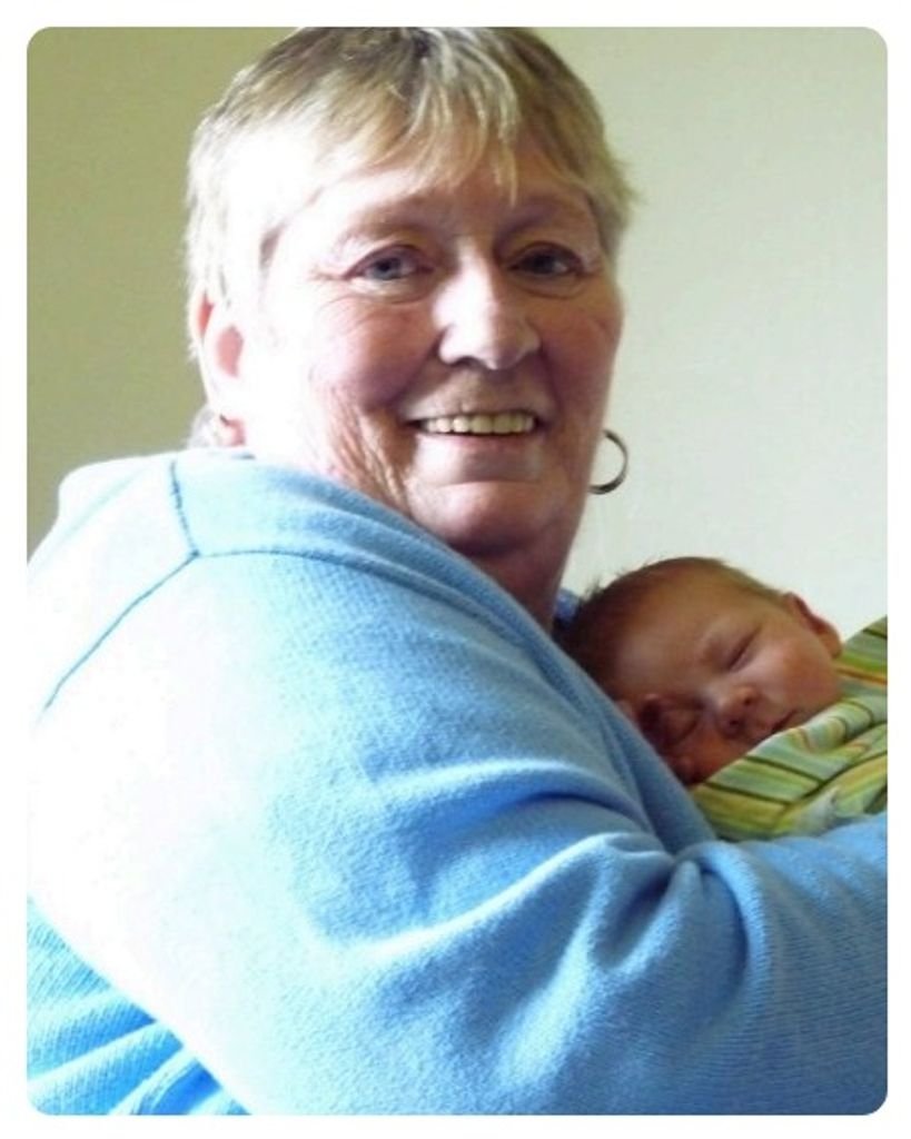 SEWELL, Donna Nadene Sewell Smiling woman holding sleeping baby.