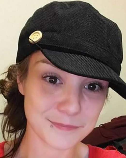 Person wearing black hat with a button.