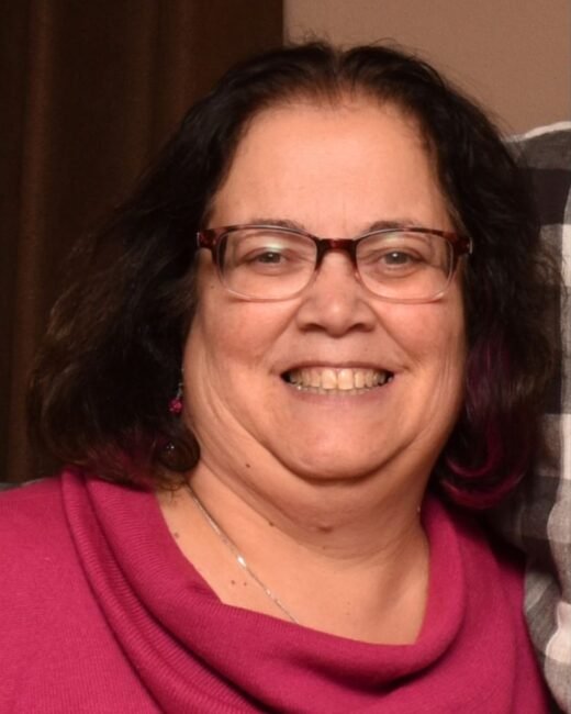 Smiling woman wearing glasses and pink shirt.