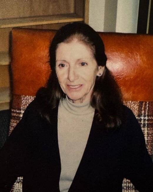Smiling woman sitting on a patterned chair.