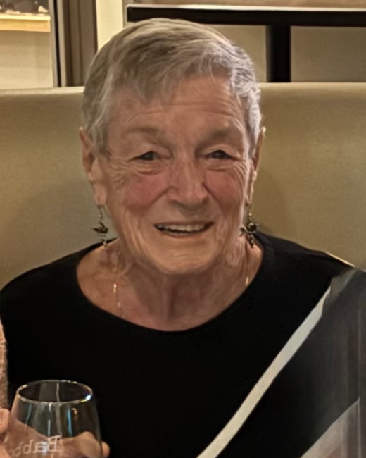 Elderly woman smiling, holding a wine glass.