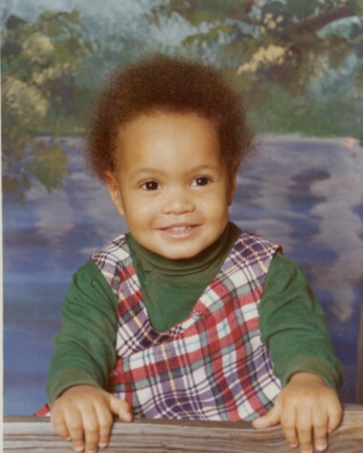 Smiling child in plaid outfit with nature background.