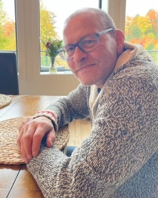 Man smiling at table with autumn view.