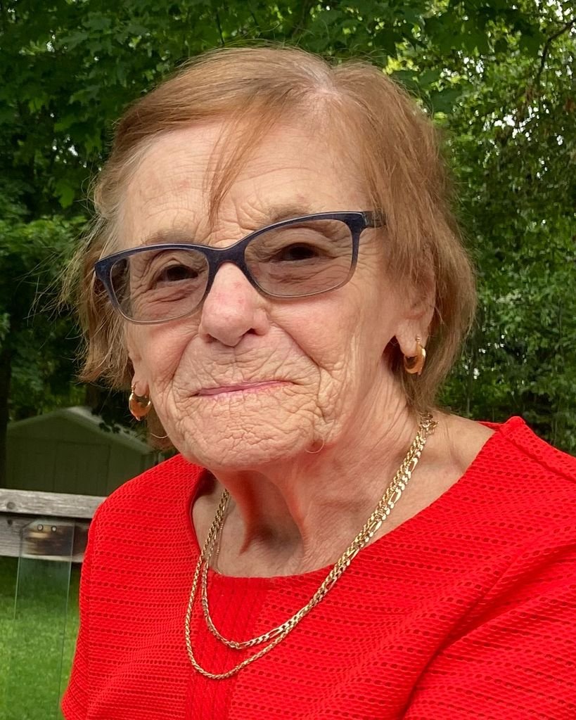 Elderly woman in glasses and red top.