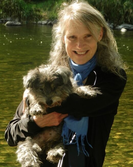 Person holding small dog by a river