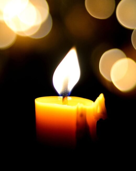 Glowing candle with soft bokeh lights background.