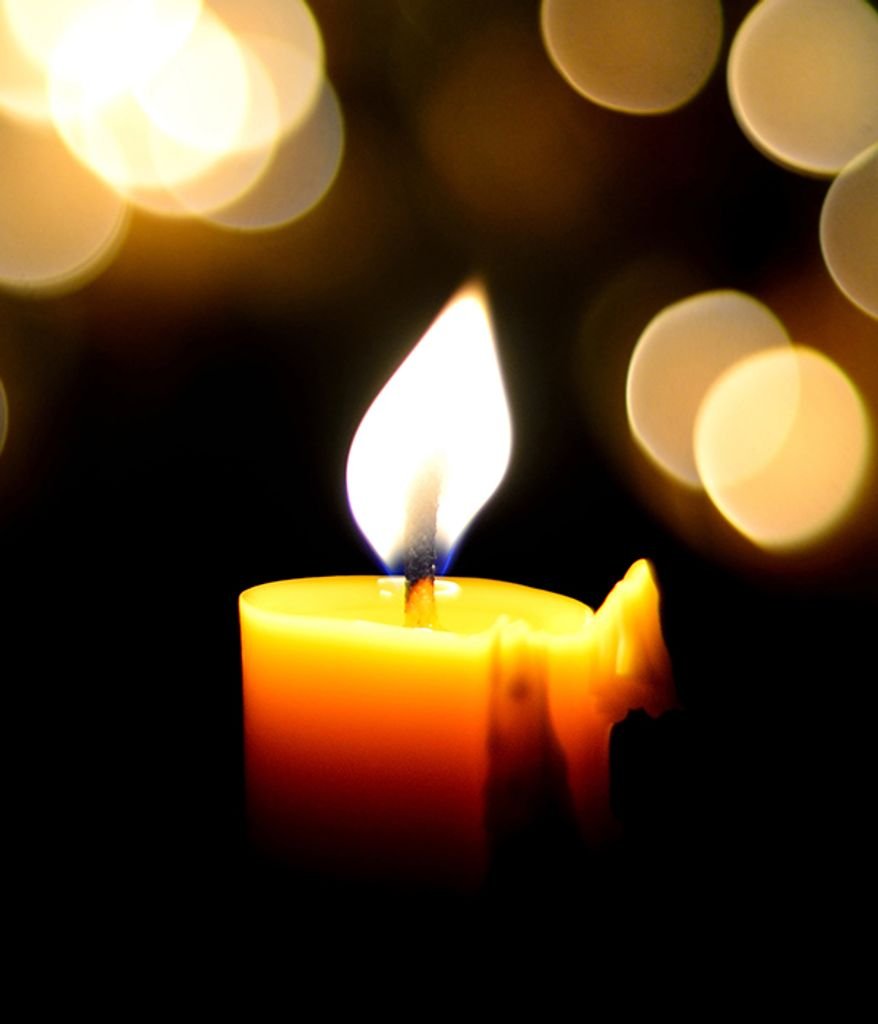 Glowing candle with soft bokeh lights background.