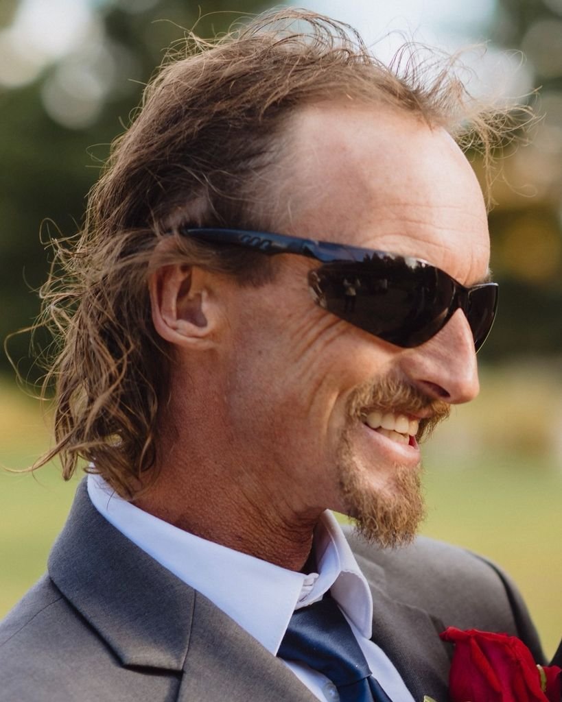 BENOIT, Lionel Gerard Benoit Smiling man in sunglasses and suit outdoors.