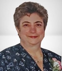 Smiling woman wearing a patterned blouse with flowers.