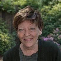 Smiling person in garden with green foliage background.