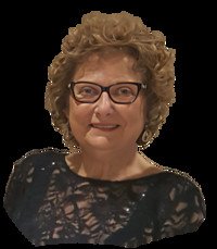 Woman with curly hair and glasses smiling.