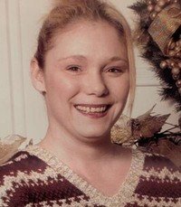 Person smiling beside holiday decorations.