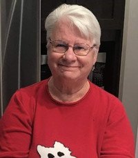 Smiling person in red shirt with white hair.