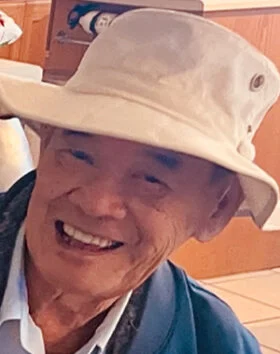 Smiling man wearing a wide-brim hat indoors.