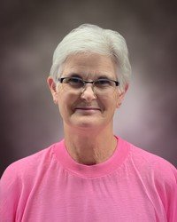 Person in pink shirt with short white hair